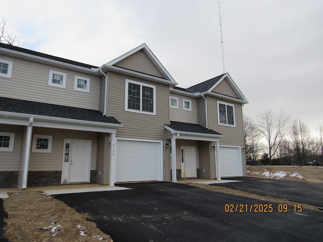 view of property featuring roof with shingles, driveway, and an attached garage