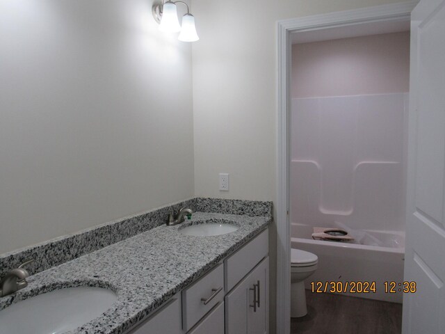 full bathroom featuring wood finished floors, a sink, toilet, and double vanity