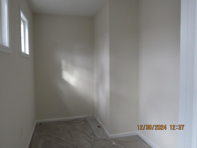 empty room featuring dark colored carpet and baseboards