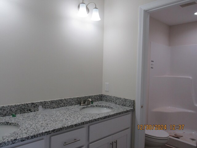 bathroom with double vanity, visible vents, toilet, a sink, and a shower stall