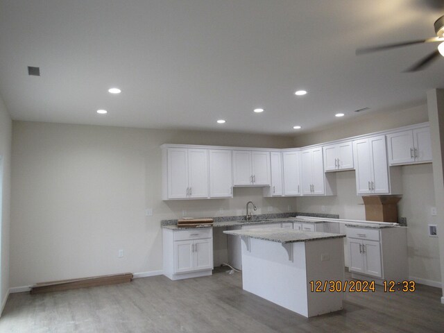 kitchen with light wood-type flooring, a kitchen island, white cabinetry, and recessed lighting