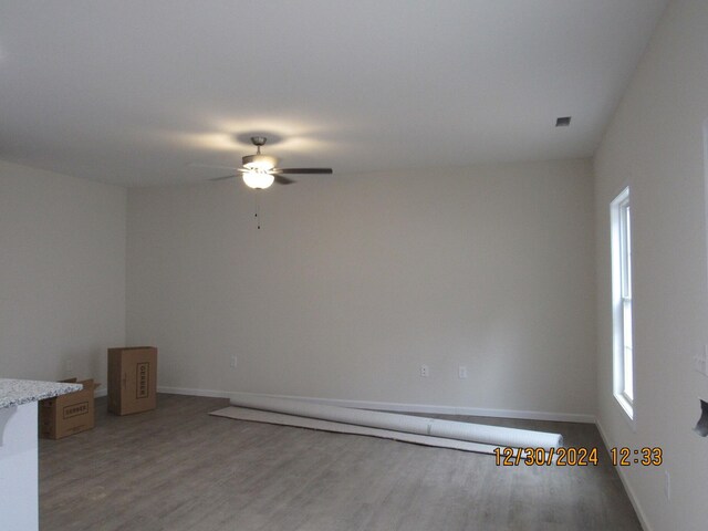 empty room featuring a ceiling fan, baseboards, and wood finished floors