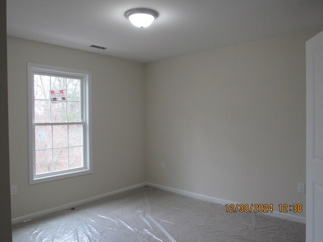 empty room featuring a wealth of natural light, visible vents, and baseboards