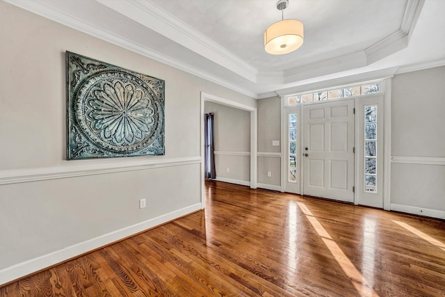 foyer entrance with hardwood / wood-style floors, a raised ceiling, and crown molding