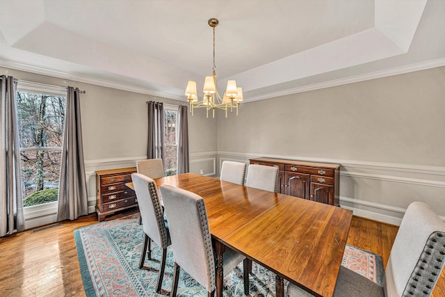 dining space featuring a notable chandelier, light wood-type flooring, and a tray ceiling