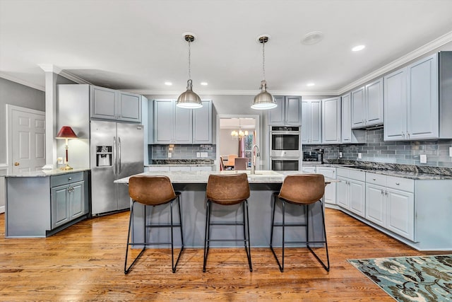 kitchen featuring gray cabinets, an island with sink, and appliances with stainless steel finishes