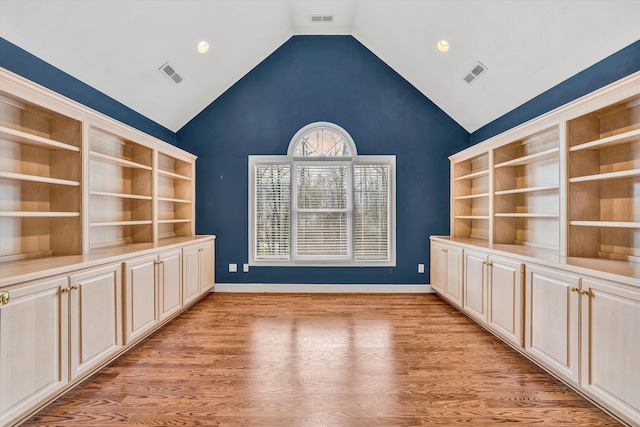 unfurnished dining area with built in shelves, light wood-type flooring, and lofted ceiling