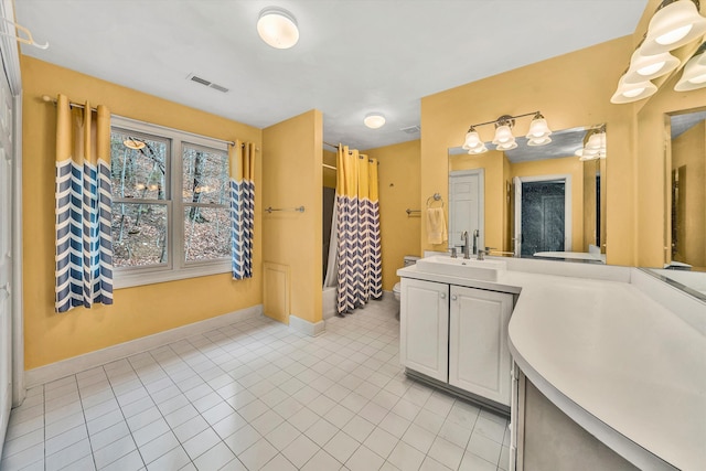 kitchen with white cabinets, sink, light tile patterned flooring, and hanging light fixtures