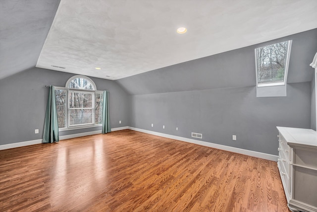 additional living space with light hardwood / wood-style floors and vaulted ceiling