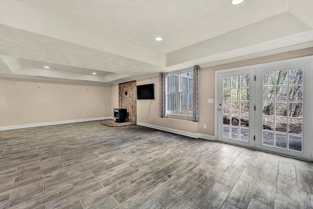 interior space with a raised ceiling and a wood stove