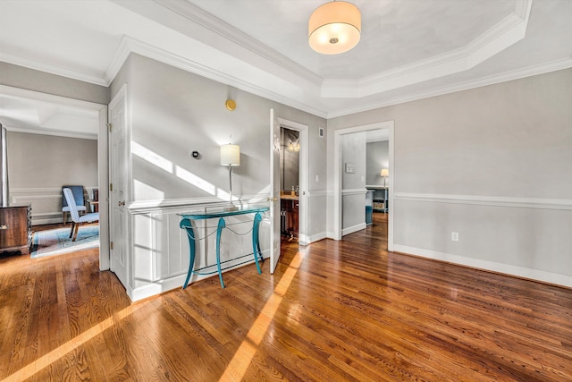 empty room with a tray ceiling, a baseboard heating unit, dark hardwood / wood-style floors, and ornamental molding