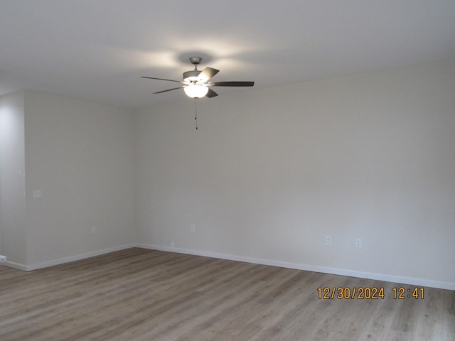 spare room featuring ceiling fan, light wood finished floors, and baseboards