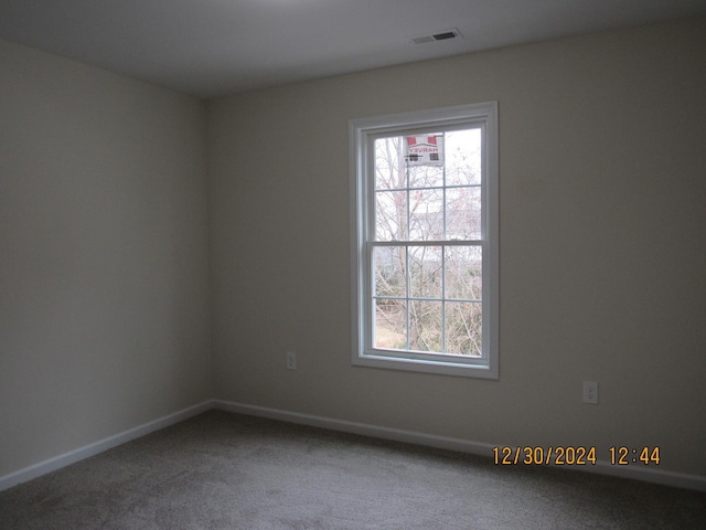 carpeted spare room featuring baseboards and visible vents