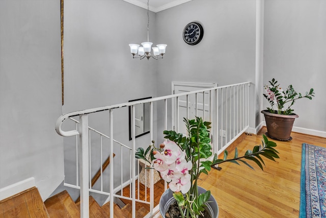 staircase with hardwood / wood-style flooring, an inviting chandelier, and crown molding