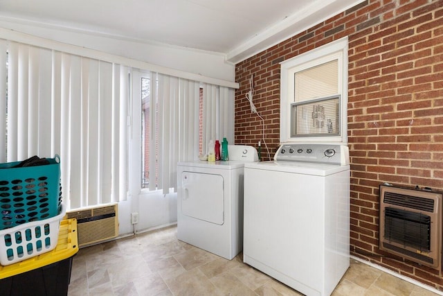 washroom with washer and clothes dryer, brick wall, and heating unit