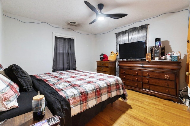 bedroom with a textured ceiling, light wood-type flooring, and ceiling fan