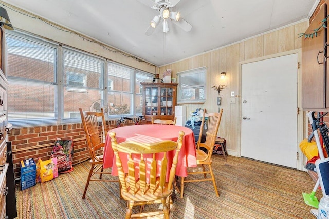 dining area with ceiling fan and wooden walls