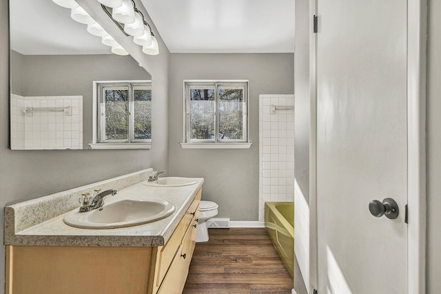 full bathroom with washtub / shower combination, wood-type flooring, vanity, and toilet