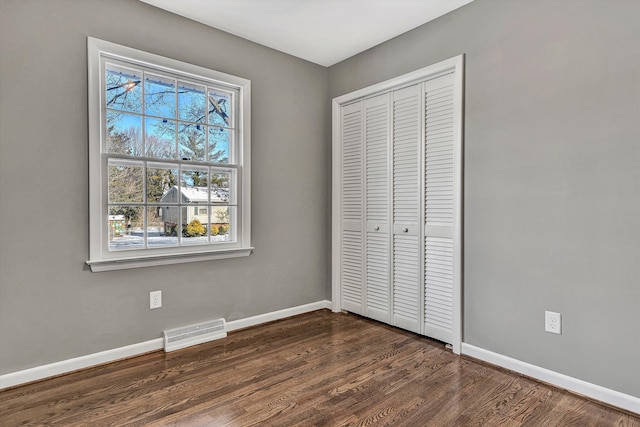 unfurnished bedroom featuring a closet and dark wood-type flooring