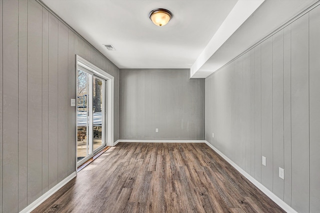 spare room featuring wooden walls and dark hardwood / wood-style flooring