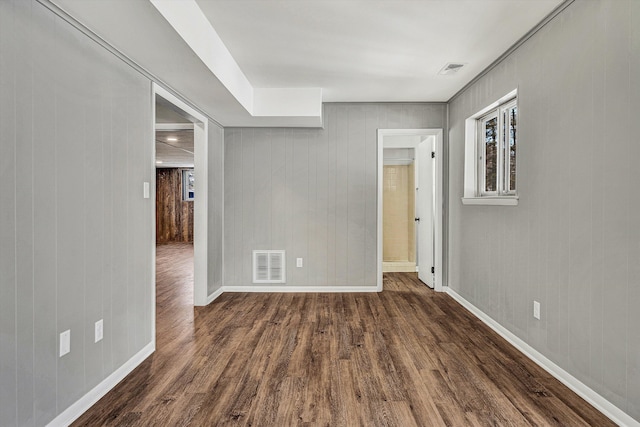 empty room with wooden walls and dark hardwood / wood-style floors