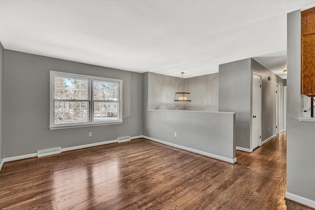 spare room featuring dark hardwood / wood-style flooring and an inviting chandelier