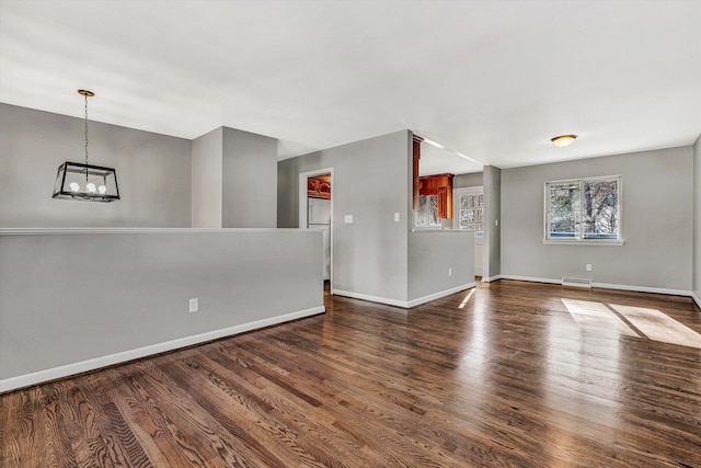 unfurnished room featuring a notable chandelier and dark hardwood / wood-style flooring