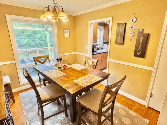 dining area with a chandelier, light hardwood / wood-style floors, and ornamental molding