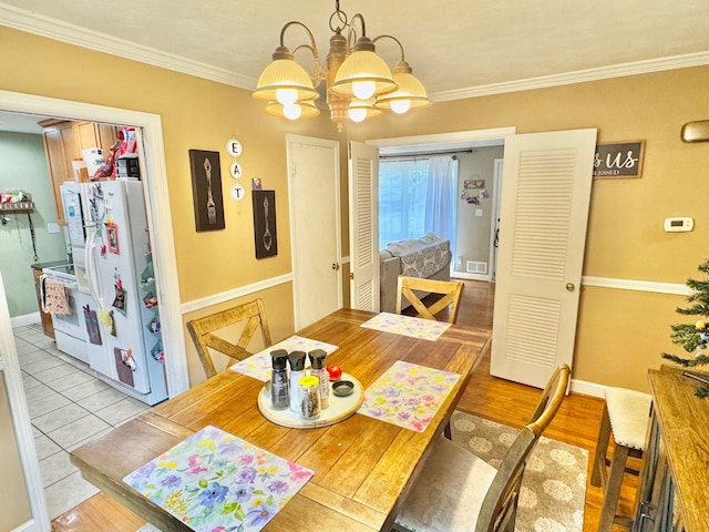 tiled dining area with a chandelier and crown molding