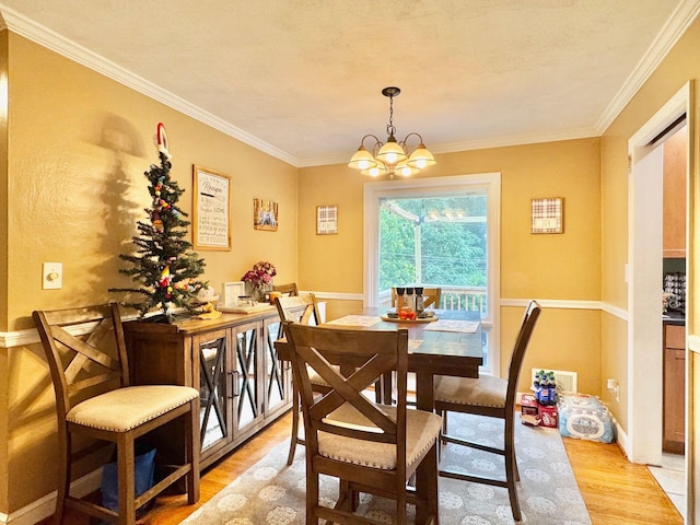 dining space featuring light wood-type flooring, an inviting chandelier, and crown molding