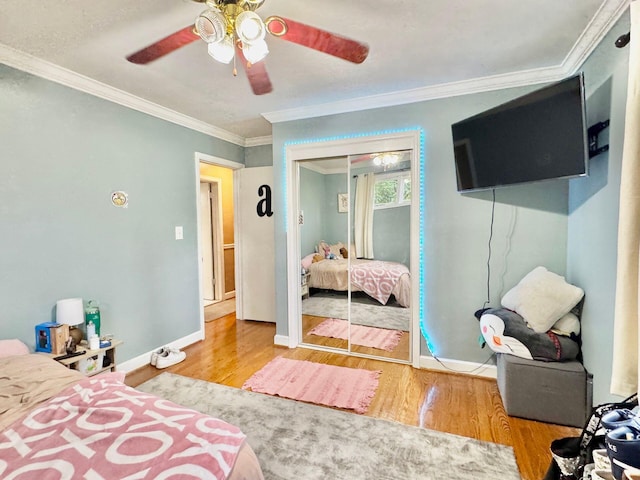 bedroom with ceiling fan, a closet, crown molding, and hardwood / wood-style flooring