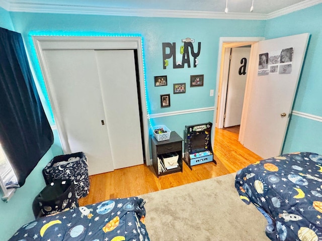 bedroom with wood-type flooring, crown molding, and a closet