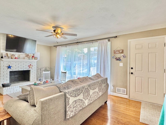 living room with hardwood / wood-style flooring, ceiling fan, a fireplace, and a textured ceiling