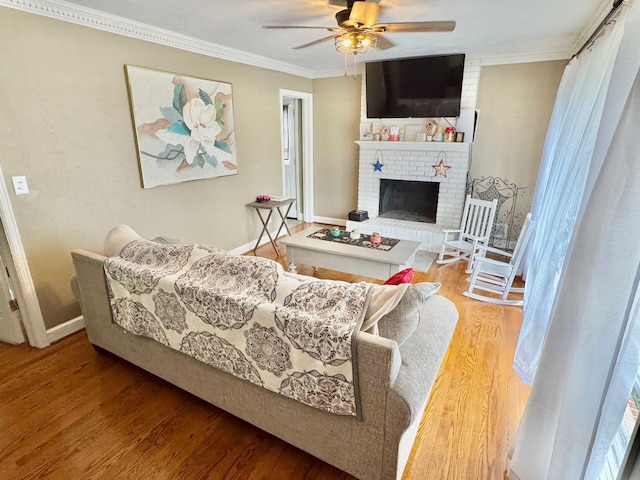 living room with hardwood / wood-style flooring, ceiling fan, crown molding, and a fireplace