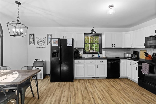 kitchen featuring black appliances, decorative light fixtures, white cabinets, and sink