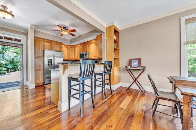 kitchen featuring a breakfast bar, appliances with stainless steel finishes, kitchen peninsula, and plenty of natural light