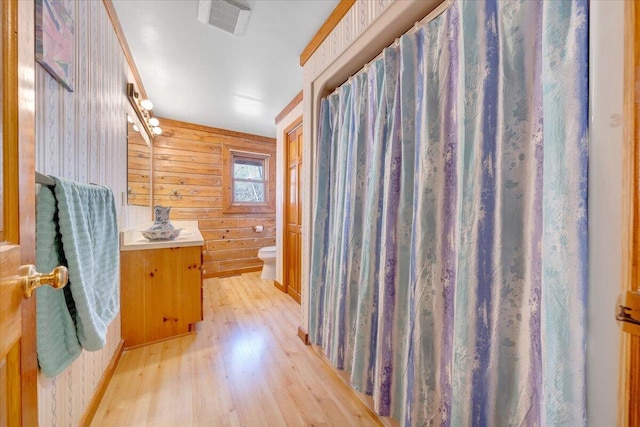 bathroom with vanity, wood-type flooring, toilet, and wood walls