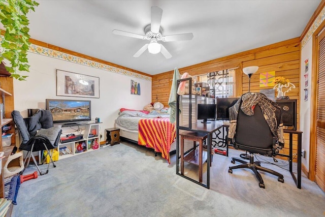 carpeted bedroom with a closet, ceiling fan, and wood walls