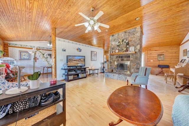 living room featuring vaulted ceiling, a stone fireplace, wooden walls, wood-type flooring, and wood ceiling