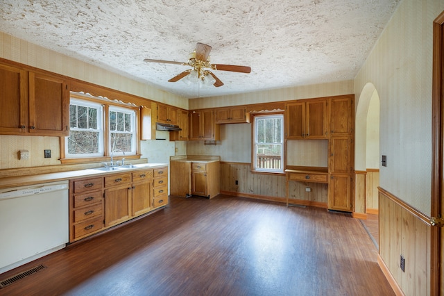 kitchen featuring a wainscoted wall, visible vents, white dishwasher, a sink, and wallpapered walls