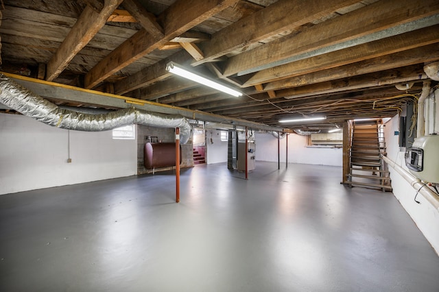 basement with heating unit, heating fuel, and stairway