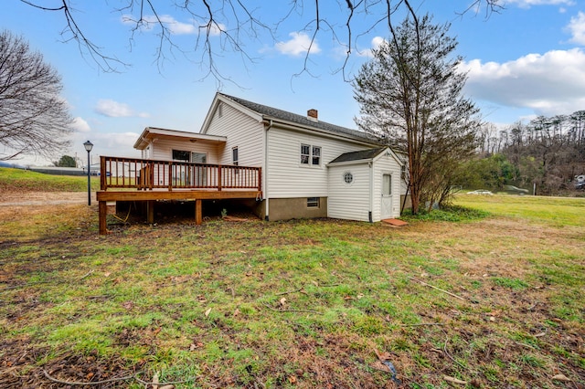 back of house featuring a yard, a chimney, and a wooden deck