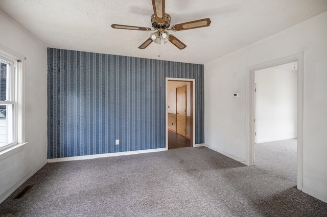 unfurnished room featuring wallpapered walls, carpet, visible vents, and a textured ceiling