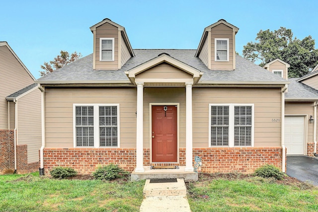 cape cod home featuring aphalt driveway, brick siding, a front yard, and a shingled roof