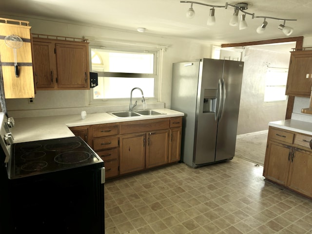 kitchen featuring stainless steel refrigerator with ice dispenser, a healthy amount of sunlight, black electric range, and sink