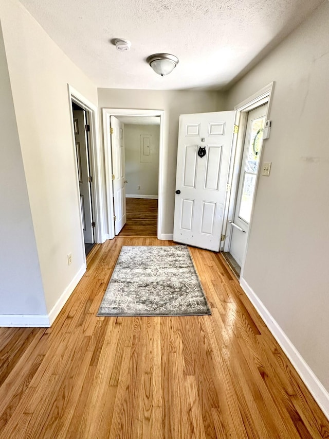 doorway to outside featuring a textured ceiling and light wood-type flooring