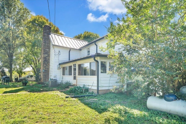 view of side of home with a yard and central AC