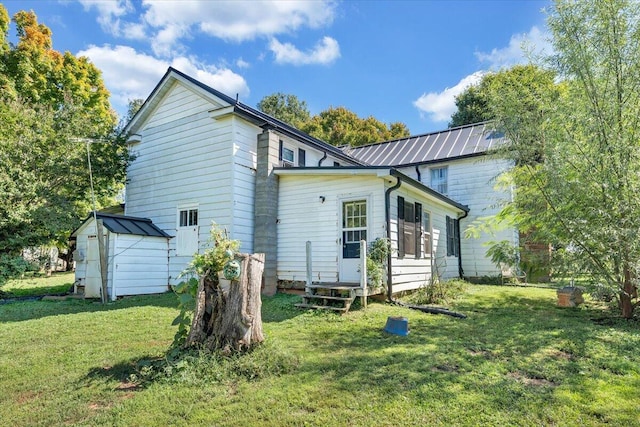 rear view of property featuring a yard and a storage unit