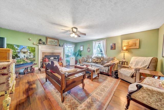 living room with hardwood / wood-style flooring, ceiling fan, and a textured ceiling