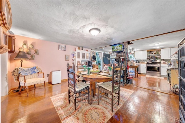 dining area featuring a textured ceiling and light hardwood / wood-style flooring